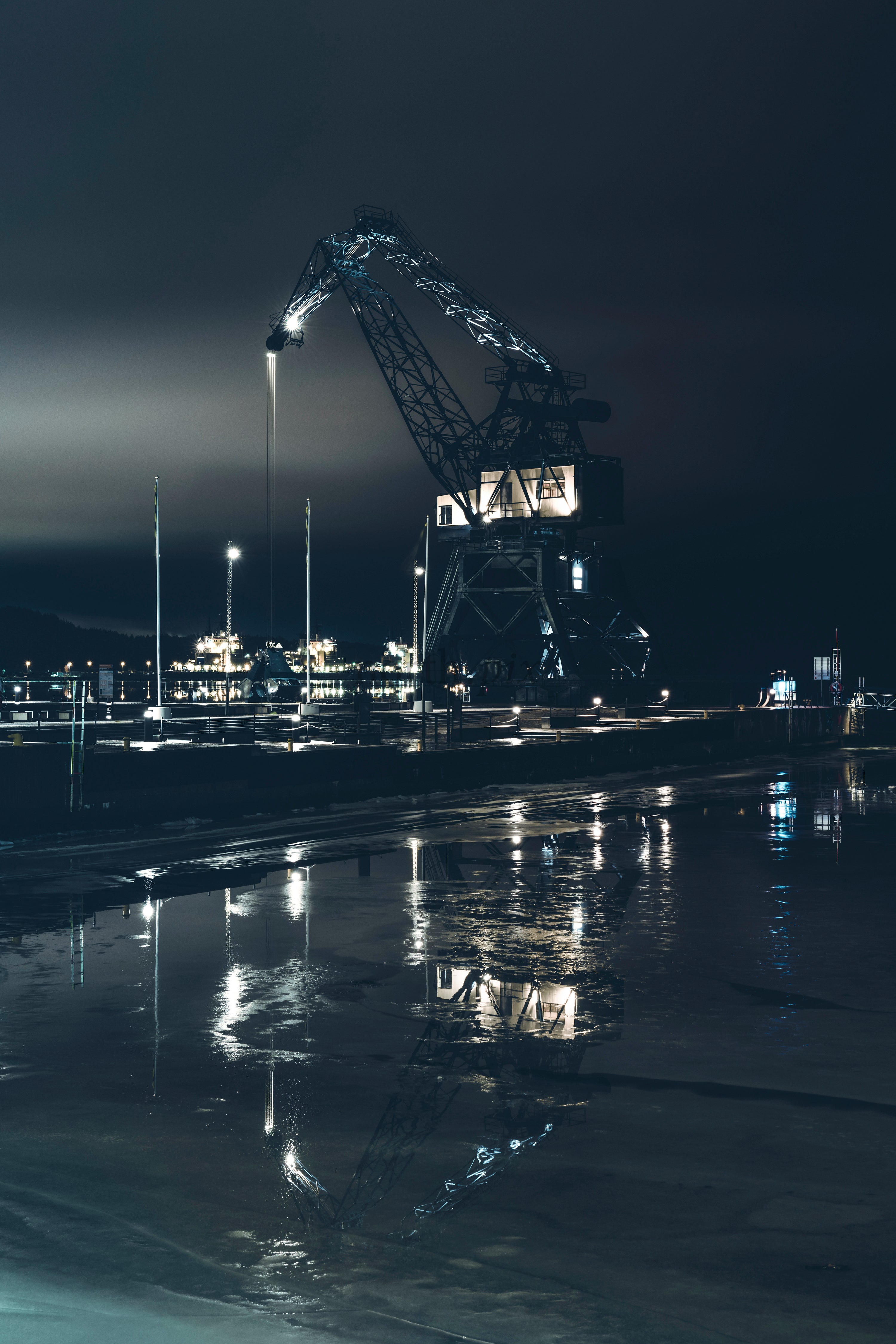 Industrial harbor crane at night with water reflection