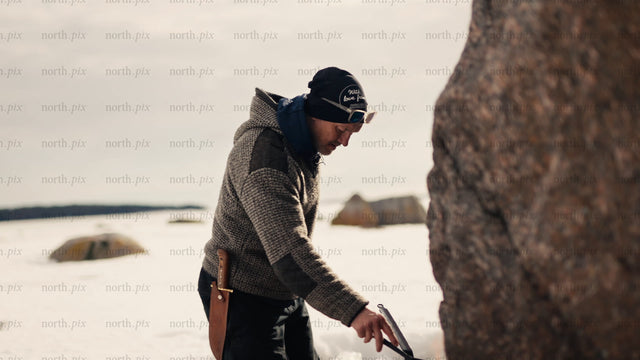 Man cooking on a portable stove by a frozen lake in Luleå archipelago winter