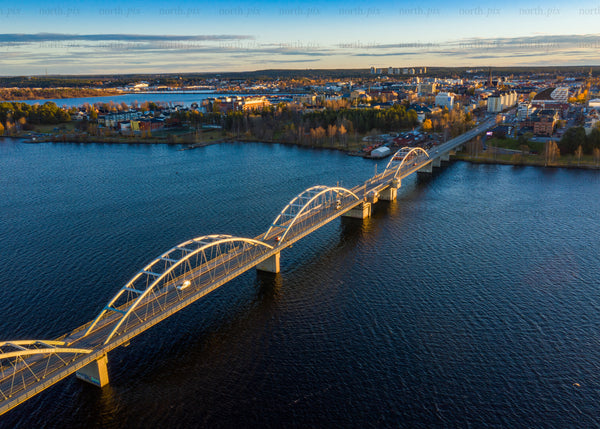 Aerial view of bridge over river during golden evening hour in Luleå