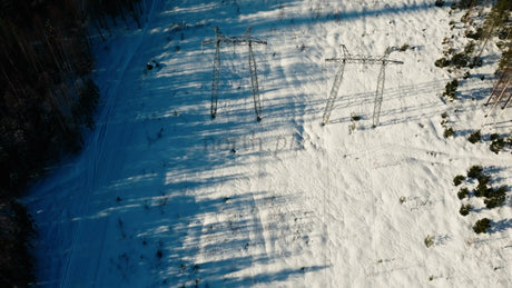 Aerial View of Wind Turbines in Snowy Winter Forest Landscape