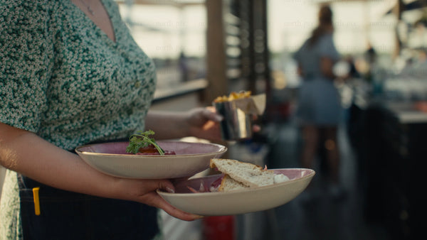 Waitress carrying food to customers at outdoor restaurant in Luleå