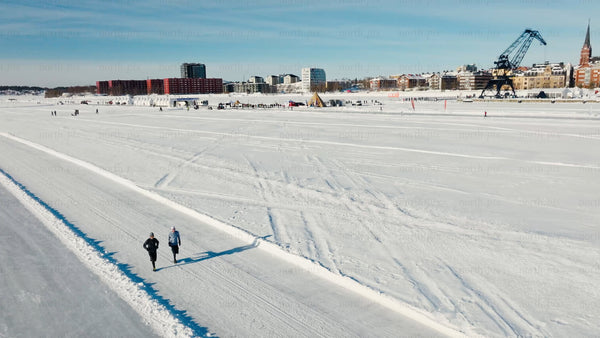Winter in Luleå: Two people running on a frozen water track