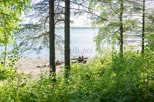 Couple on bench by lake shore in summer