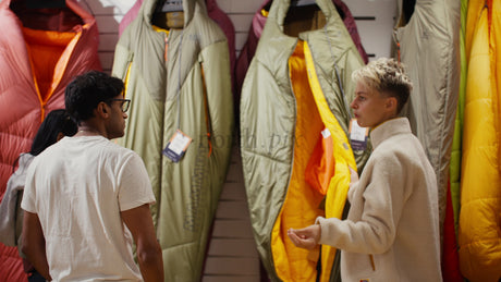 Family Shopping for Sleeping Bags in a Camping Store with Saleswoman