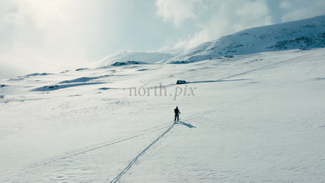 Lone Skier Crosses Snowy Expanse in Mountainous Winter Landscape