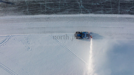 Aerial Drone Footage of Snow Blower Clearing Path on Frozen Lake in Lulea, Sweden During Winter