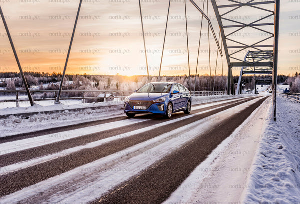 Blue car crossing a bridge at sunset in winter