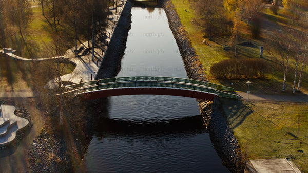 Autumn day in Piteå city: Person walks over a canal bridge with golden sunlight