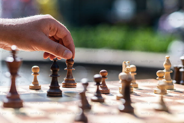 Hand moving a chess piece on an outdoor board