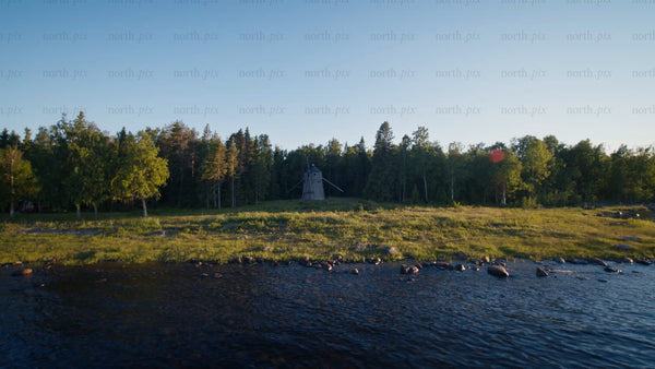 Summer evening in Luleå archipelago: Drone view of windmill, coastline, and forest at golden hour