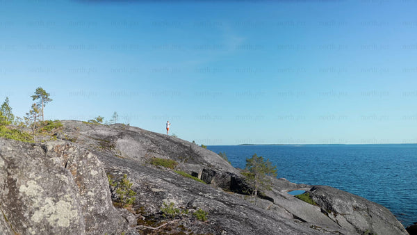 Man on rocky cliff overlooking Baltic Sea in Luleå archipelago during summer