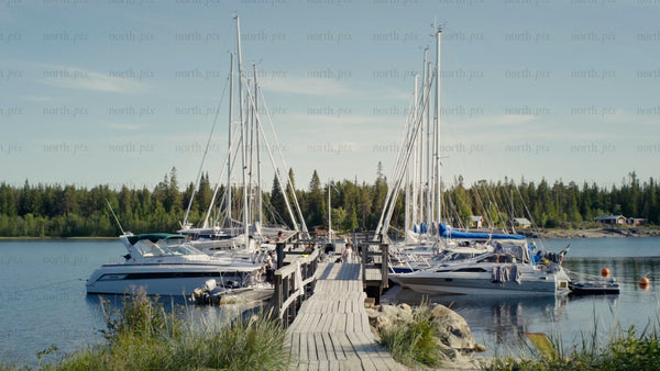 Summer day at Kluntarna archipelago: Sailboats and motorboats moored at wooden dock, Luleå
