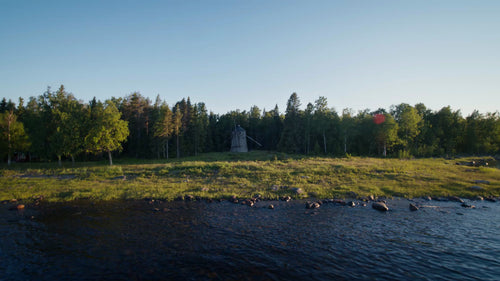 Sommarkväll i Luleå skärgård: Drönarvy över väderkvarn, kustlinje och skog vid gyllene timmen