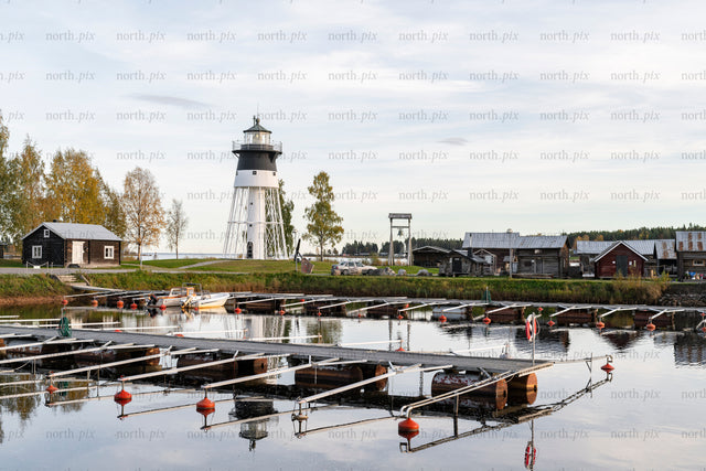 Lighthouse and marina with wooden boathouses in autumn