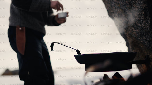 Man cooking on open fire on winter beach in Luleå archipelago