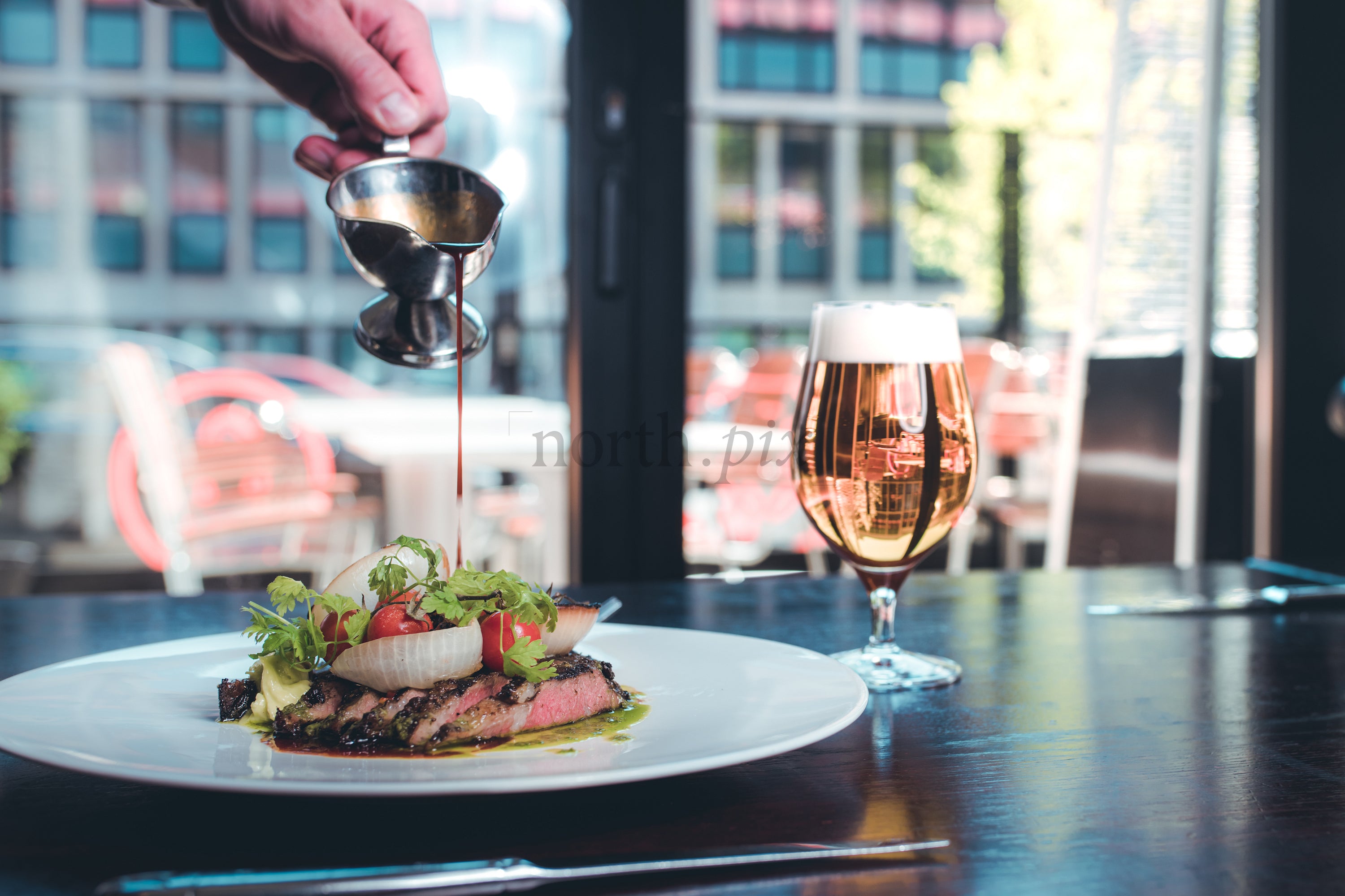 Plated steak with sauce and beer at restaurant, daytime