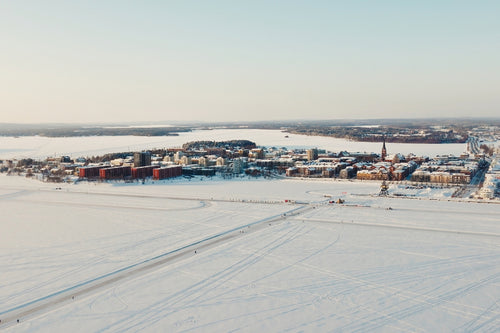 Flygfoto över Luleå centrum i vinterns snöiga landskap över frusen sjö och byggnader