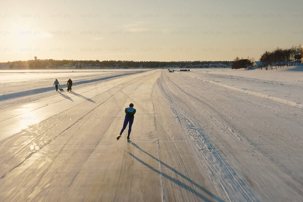 Ice skating along a snowy lake at sunset in Luleå city center, winter scene