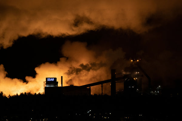 Steel mill at night with glowing smoke and lights