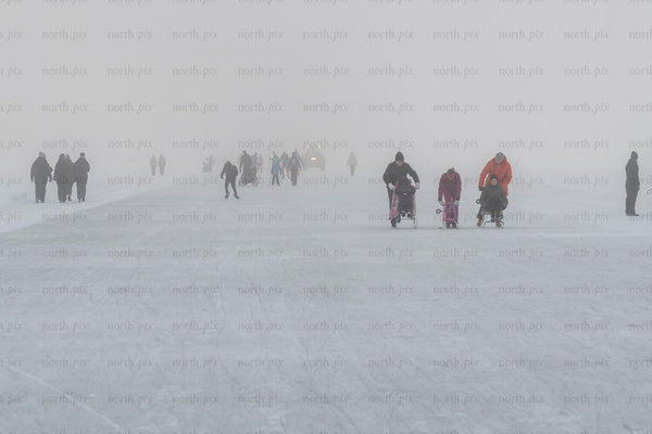 People skating and pushing sleds on frozen lake, winter