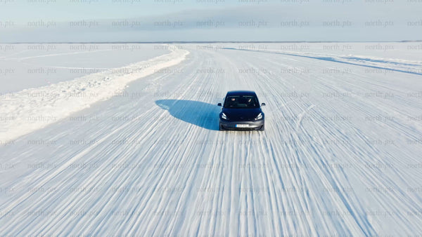 Tesla/car driving on snowy ice road in winter, Luleå - drone shot