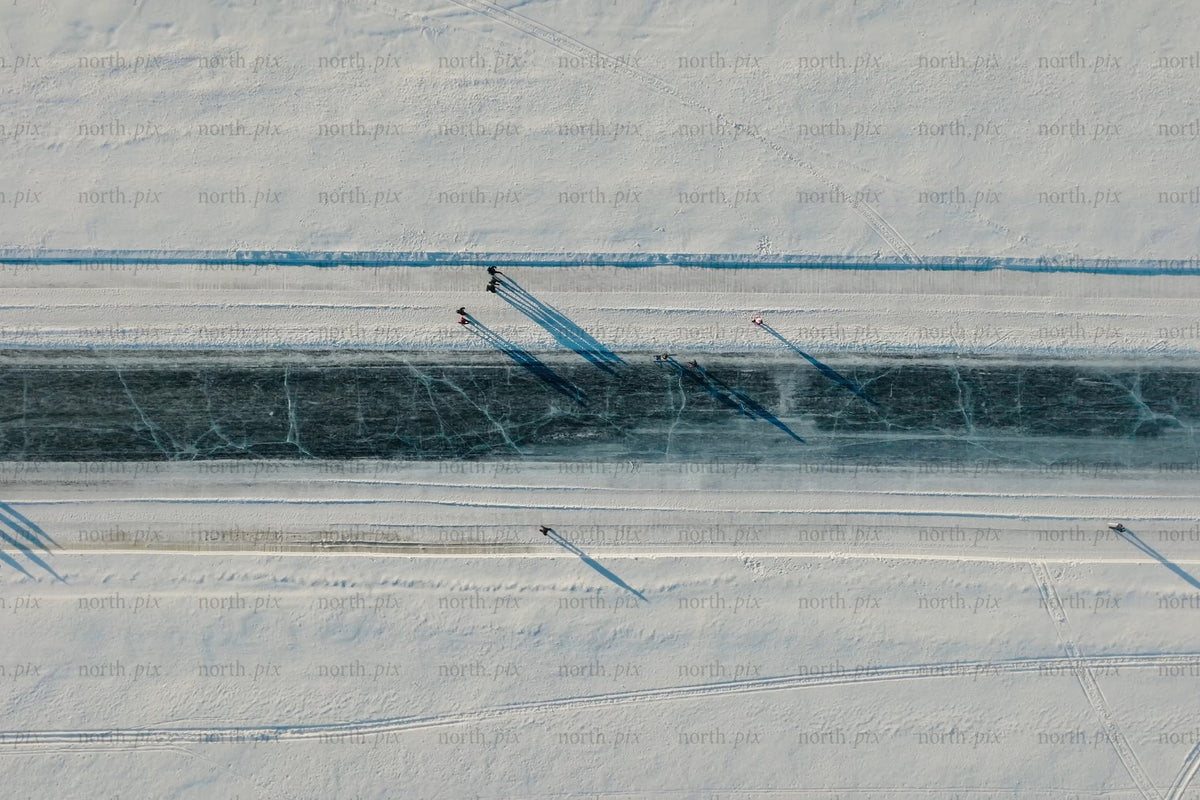 Aerial view of snowy canal in Luleå city center with skaters and long shadows