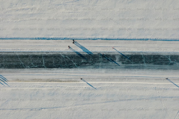 Aerial view of snowy canal in Luleå city center with skaters and long shadows