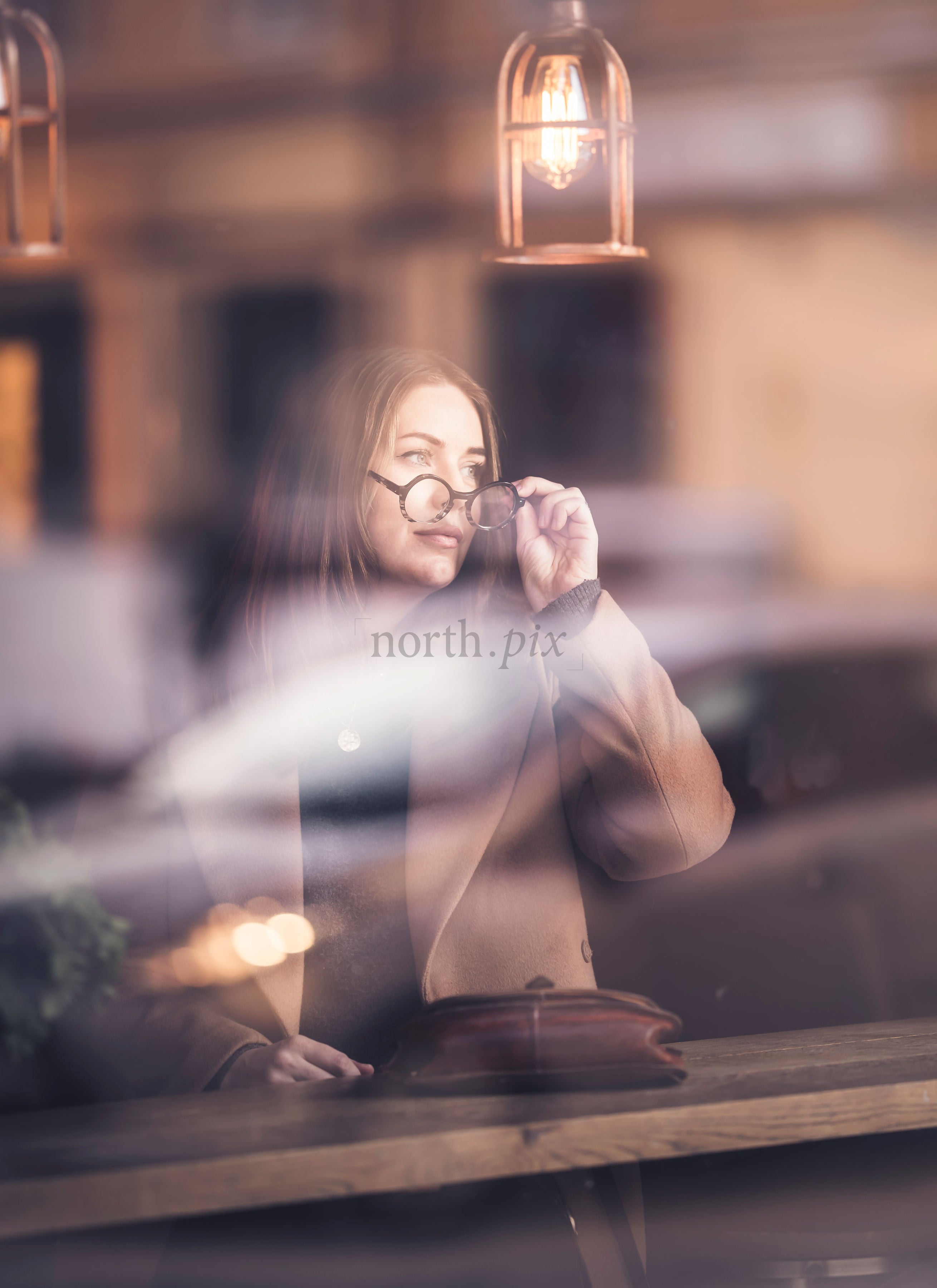 Woman looking out café window in evening light