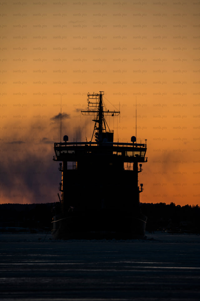 Icebreaker ship silhouette at sunset over ice