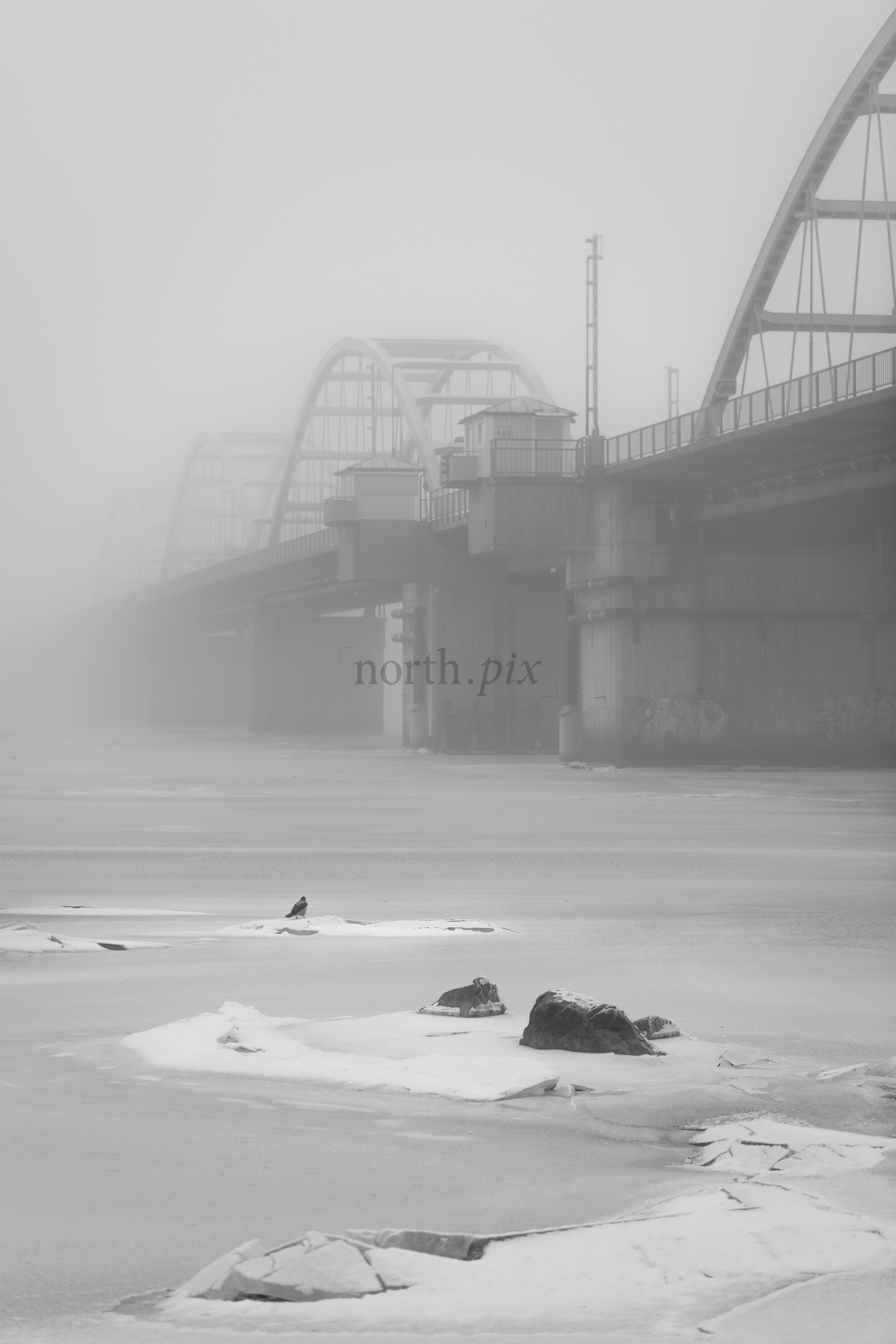 Bridge over frozen river in heavy fog