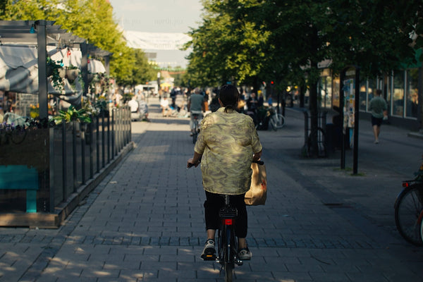 Cyclist riding through Luleå city center with outdoor cafes and busy pedestrian street