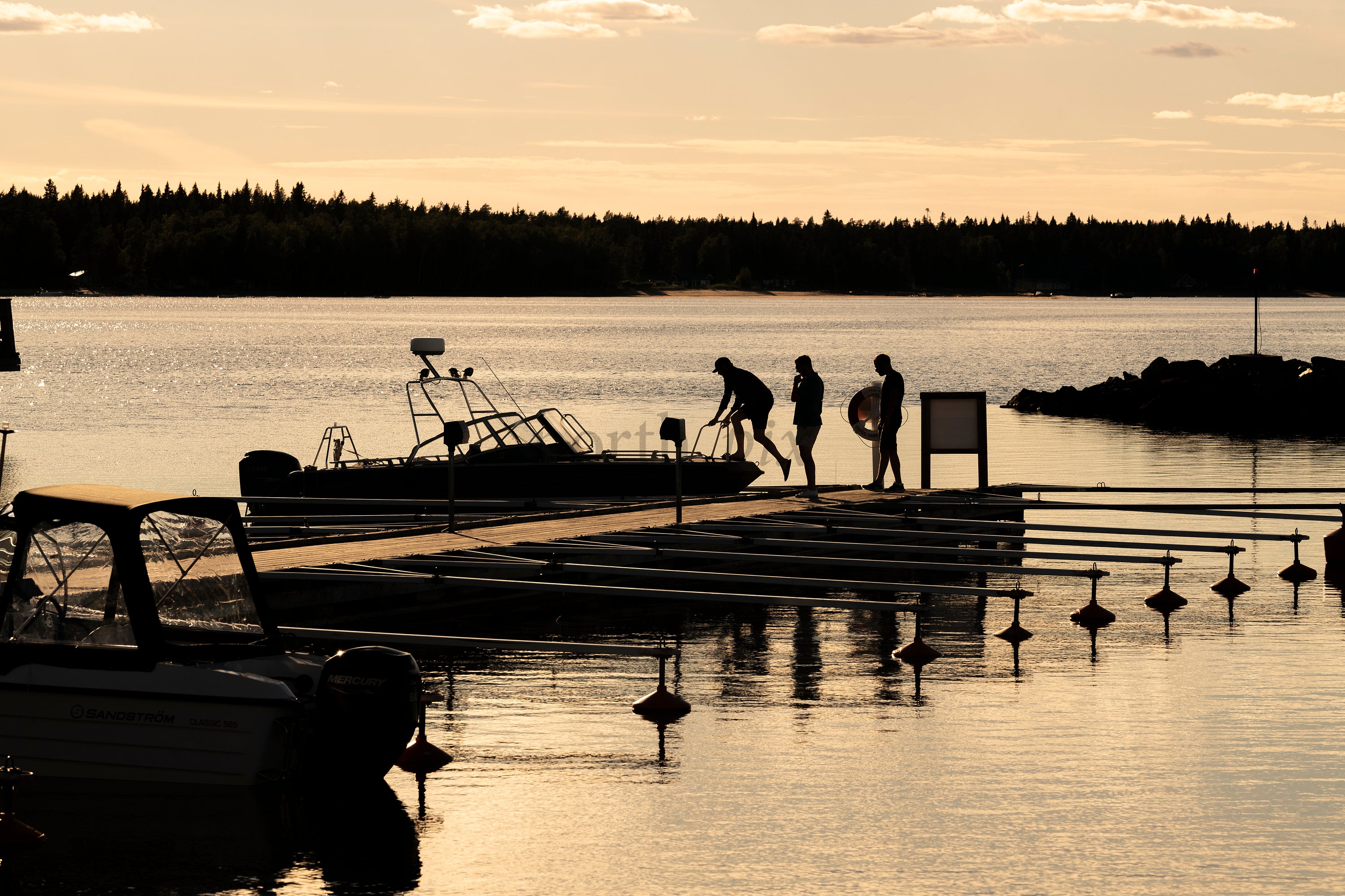 People boarding boat at dock at sunset
