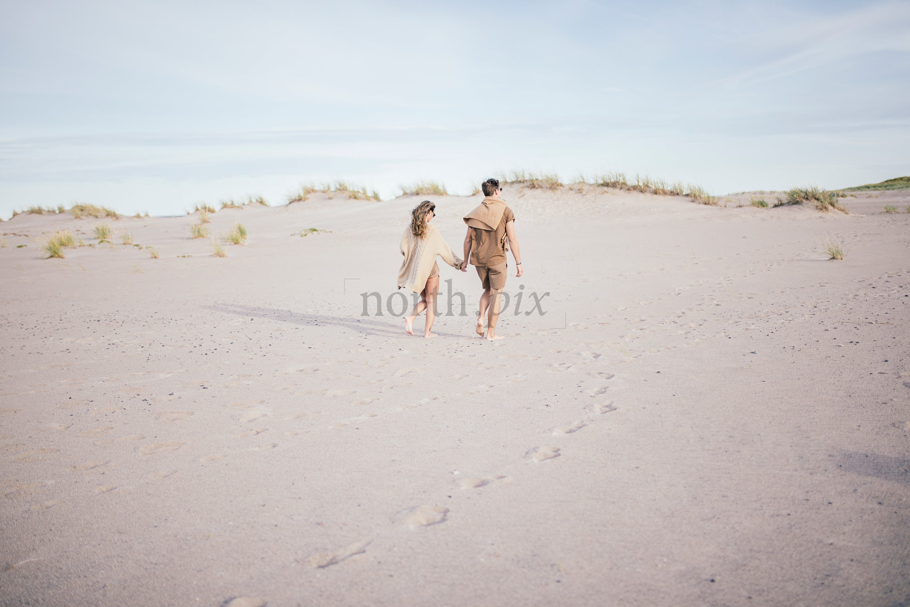 Couple walking on sand dunes at midday