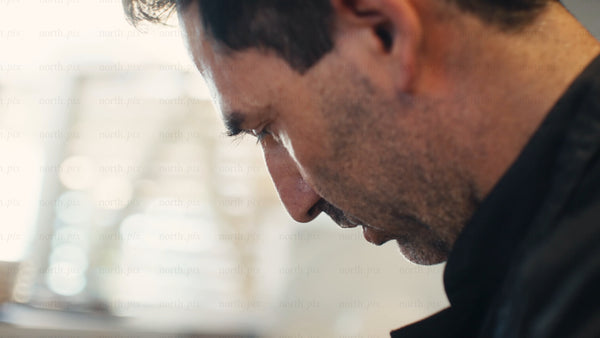 Focused chef in black uniform prepares food in a professional kitchen