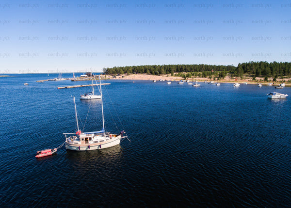 Drone shot of boats anchored by a sandy beach during a summer day