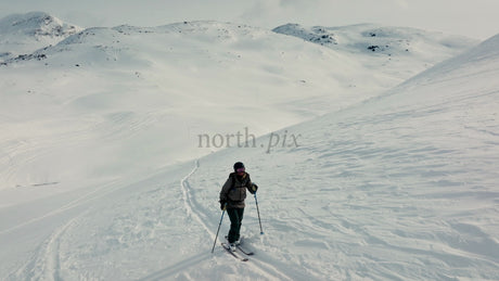 Skier Ascends Snowy Mountain at Riksgransen, Sweden, in Winter