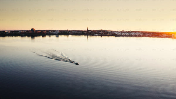Sunset over Luleå: A boat sails across the calm water of the Swedish city