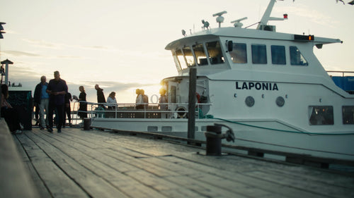 Urban sommarkväll: Passagerare som går ombord på turbåt vid solnedgången i Luleå, Sverige
