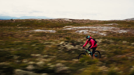 Man in Red Jacket on Mountain Bike Rides Downhill Trail
