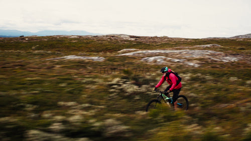 Man i röd jacka på mountainbike rider utförsbacke