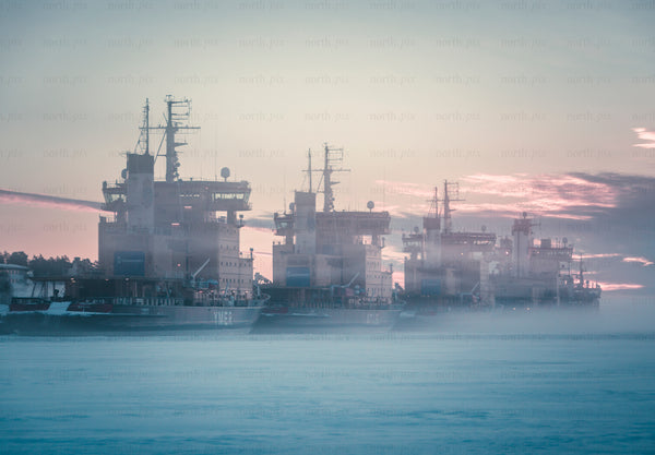Icebreakers moored in icy harbor at sunrise