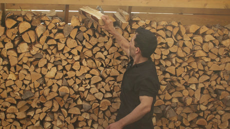 Man Stacking Firewood in Woodshed: Preparing for Winter