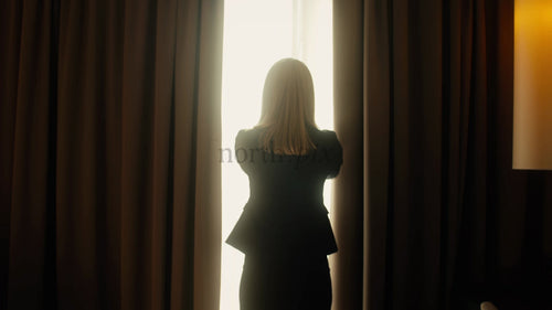 Affärskvinna öppnar gardinerna i hotellrummet till ljus solig dag