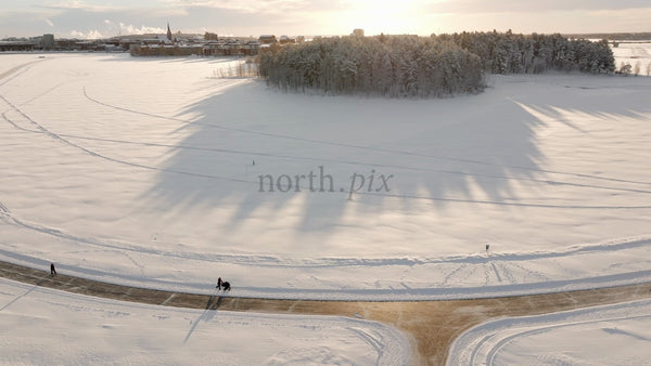 Winter Wonderland in Lulea: Aerial View of Snowy Landscape with People Strolling Along Path