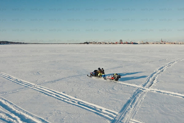 Snowy day sledding on frozen lake near Luleå city center with family and friends