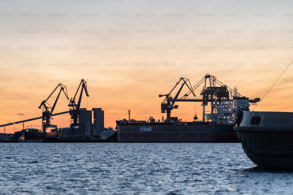 Cargo ship loading at industrial port of Luleå during sunset