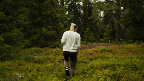 Kvinna vandrar genom en sommarskog i Luleå, Sverige