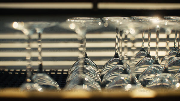 Wine glasses glimmering on bar counter in sunlight: A celebration of luxury lifestyle