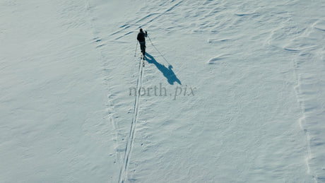 Skier Crosses Snowy Mountain on Sunny Winter Day