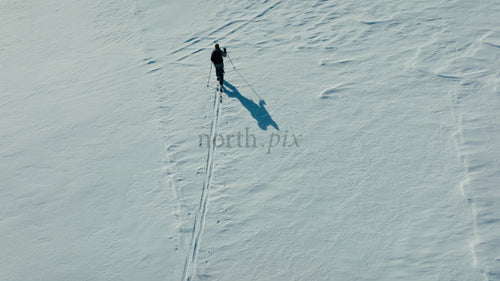 Skidåkare korsar snötäckt berg på solig vinterdag